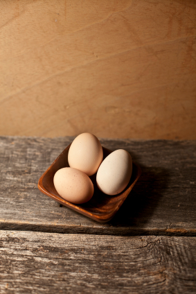 Free range chicken eggs in a wooden bowl on a rustic wooden board